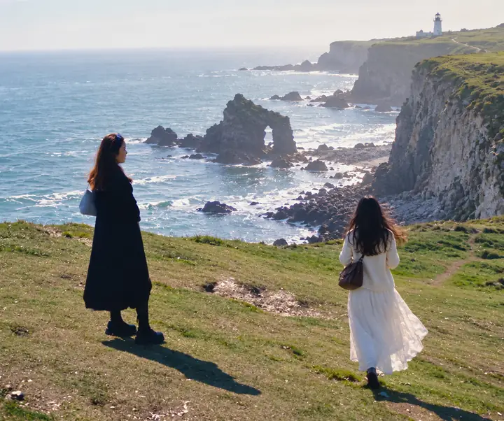 Portrait outdoors with a distracting figure near a coastal cliff